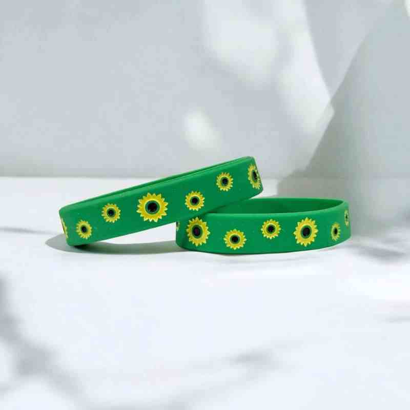 Pulseira de silicone verde com estampa de girassóis amarelos e detalhes em preto, ideal para acessórios estilosos e contemporâneos.